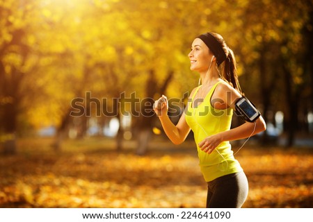Female fitness model training outside on a warm fall day and listening to music. Sport lifestyle.