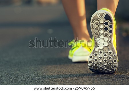 Runner woman feet running on road closeup on shoe. Female fitness model sunrise jog workout. Sports healthy lifestyle concept.