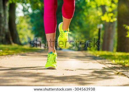 Runner woman feet running on road closeup on shoe. Female fitness model sunrise jog workout in a sunny park outdoors. Sports healthy lifestyle concept.