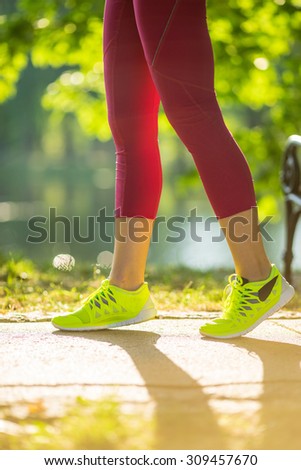 Runner woman feet running on road closeup on shoe. Female fitness model sunrise jog workout in the sunny park outdoors. Sports healthy lifestyle concept.