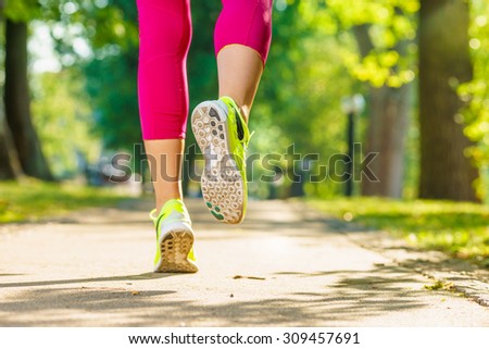 Runner woman feet running on road closeup on shoe. Female fitness model sunrise jog workout in a sunny park outdoors. Sports healthy lifestyle concept.