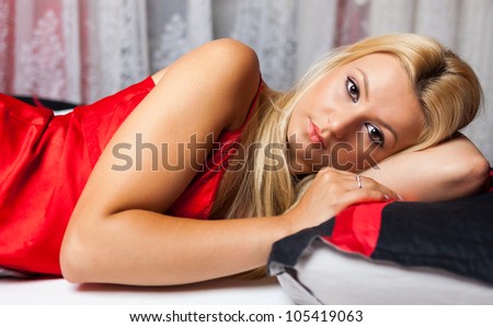 Gorgeous blond young woman lying in bed in red underwear