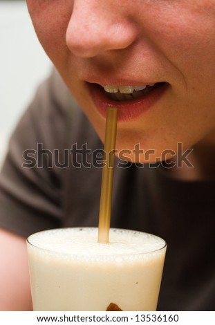 Close-up of a woman\'s mouth drinking cappuccino in a pub