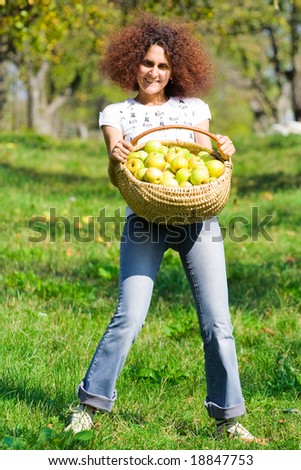 Pretty redhead woman with a basket full of apples, in an orchard