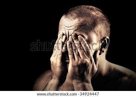 Low key portrait of an young man covering his eyes