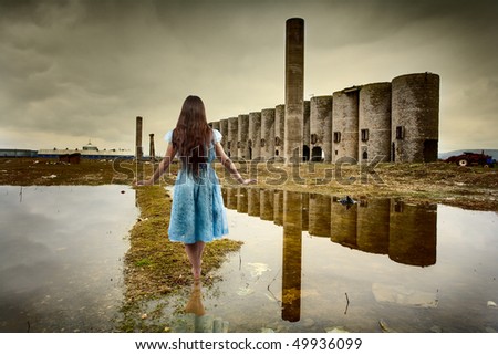 Barefoot young woman walking in a deserted industrial landscape