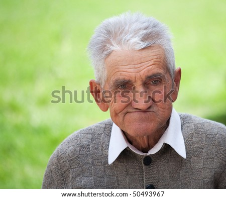 Close up portrait of an old farmer over blurred green background