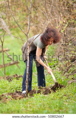 Young redhead lady working with a hoe in the countryside