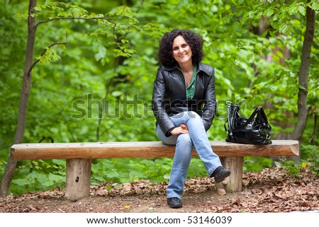 Portrait of an attractive caucasian woman sitting on a bench in the forest