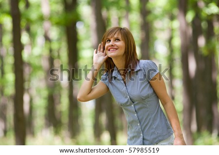 Beautiful young woman relaxing in the forest and listening nature sounds