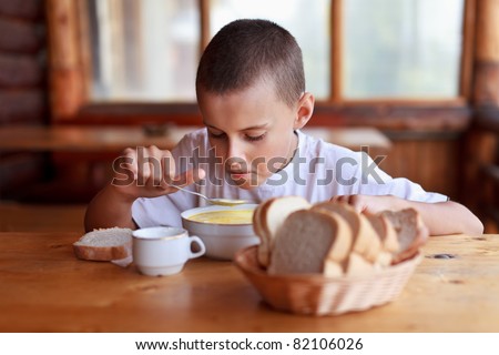 Boy eating soup for dinner in a rustic restaurant outdoor