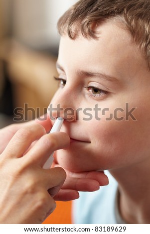 Woman doctor hands giving a boy a dose of nasal spray against flu