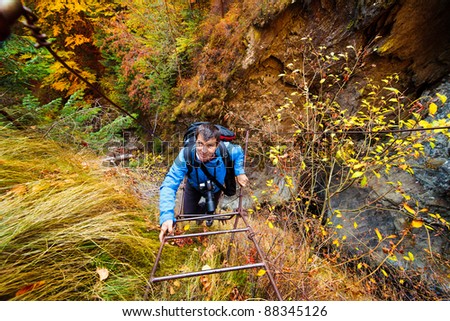Mountaineer climbing a rusty iron ladder on a mountain