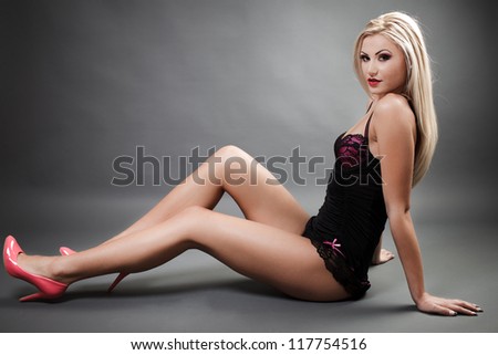 Full length portrait of a beautiful woman wearing lingerie while sitting on the floor