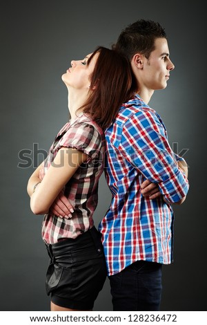 Closeup of sad young couple standing back to back,having relationship difficulties. Gray background