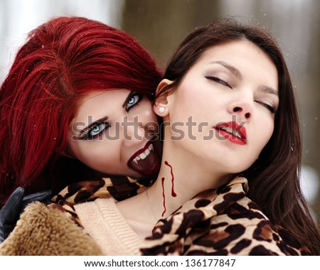 Closeup of a redheaded vampire biting innocent girl