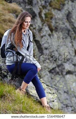 Woman hiker with backpack resting on a rock