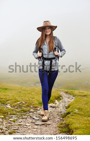 Female hiker with backpack and hat on a mountain trail