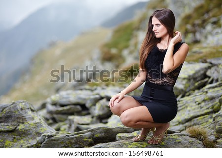Elegant woman in dress sitting on the rocks