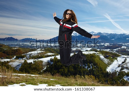 Young hiker woman jumping for joy outdoor in an alpine landscape