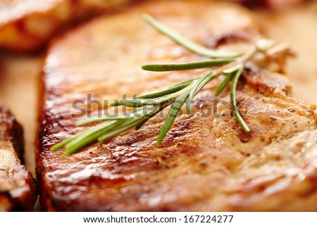 Closeup of spiced fried pork chop decorated with rosemary on a wooden board, selective focus