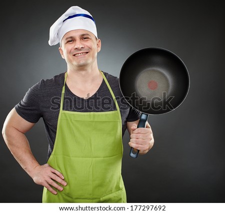 Caucasian chef in apron and hat, with wok pan over gray background