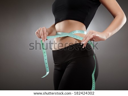 Closeup of a young and fit woman\'s waist with measuring tape