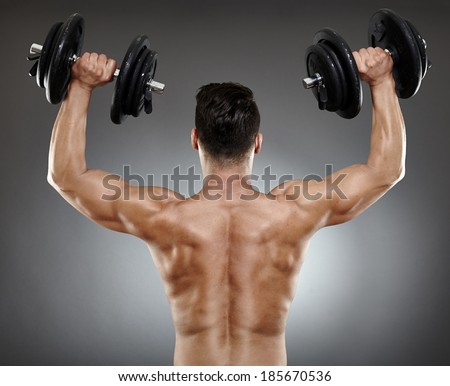 Back of a bodybuilder working with dumbbells for triceps and deltoids