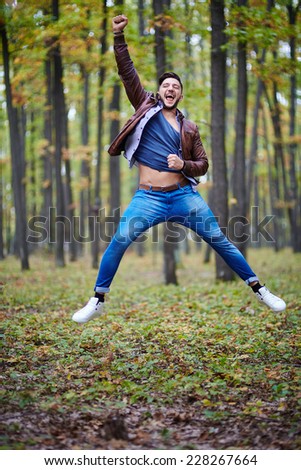 Young man jumping for joy outdoor in the forest