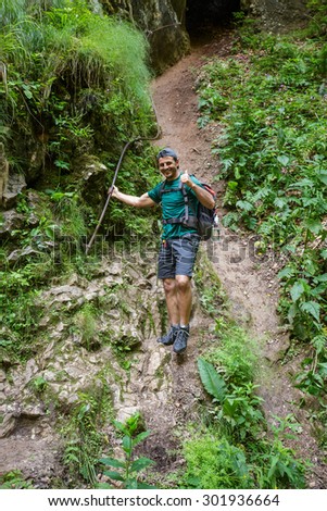 Man hiker getting out from a cave holding on to a safety cable