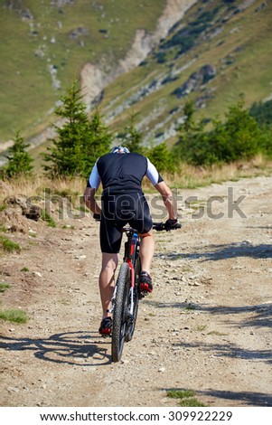 Mountain bike cyclist in sport equipment and helmet riding on rugged trails
