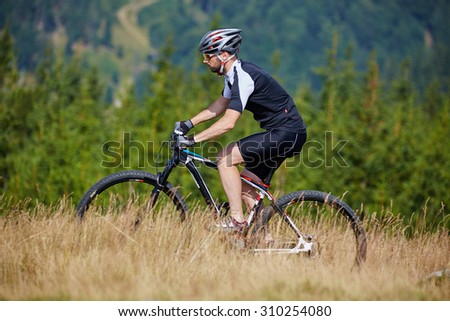 Mountain bike cyclist in sport equipment and helmet riding on rugged trails