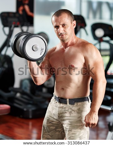 Caucasian man doing biceps curl with dumbbells in a gym with selective focus