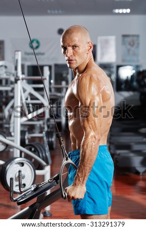 Ripped athlete bodybuilder doing a triceps workout at a cable machine