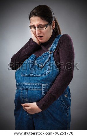 Studio portrait of a young pregnant woman with pregnancy pain