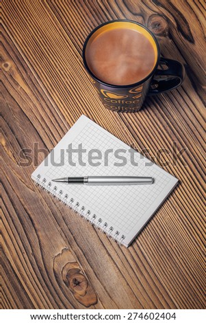 notepaper, coffee cup and pen on wood table