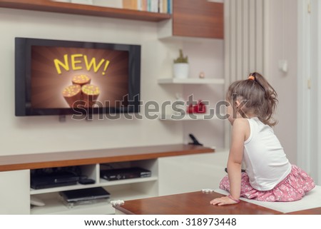 cute little girl watching advertisement on tv