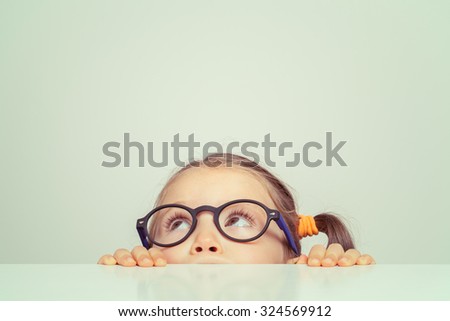 Similar – Image, Stock Photo A little girl hides under the table and looks out from under it. The girl plays in the break between homework. Homework, homeschooling, online learning