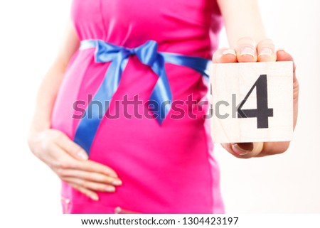 Pregnant woman in pink dress with blue ribbon showing number of fourth month of pregnancy, concept of extending family and expecting for newborn 商業照片 © 