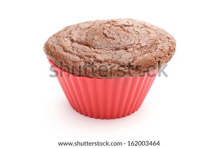 Closeup of fresh baked muffin with cacao and chocolate in red silicone cup. Isolated on white background