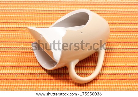 Closeup of broken cup, shattered cup, damaged mug lying on orange cloth