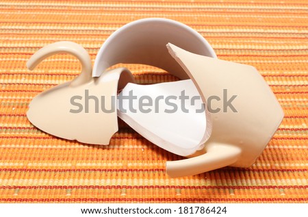 Closeup of broken cup, shattered cup, damaged mug lying on orange cloth