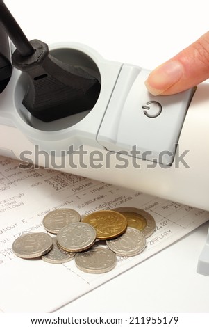 Finger of woman turns off electrical extension, electrical plugs connected to electrical power strip, electricity bill with coins, concept for energy saving