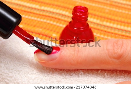 Red nail polish applied to the nail of hand, manicure process, nail care