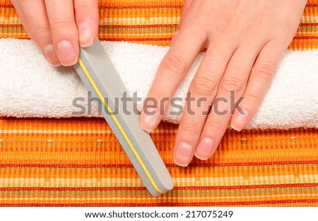 Woman with file filing nails, woman polishing nails, manicure, nail care