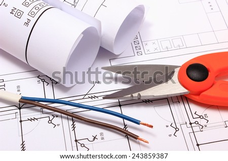 Cable cutter, electric wire and rolls of electrical diagrams lying on construction drawing of house, accessories for engineer jobs