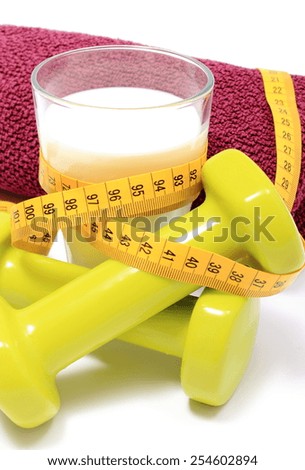 Green dumbbells and purple towel for using in fitness, measure tape and glass of fresh milk, concept for slimming, healthy lifestyle and nutrition