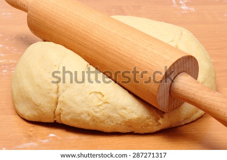 Yeast cake and rolling pin lying on wooden table, preparing yeast cake.