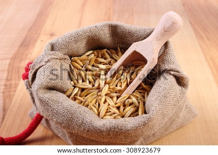 Heap of organic oat grains with wooden spoon in jute bag, healthy food and nutrition