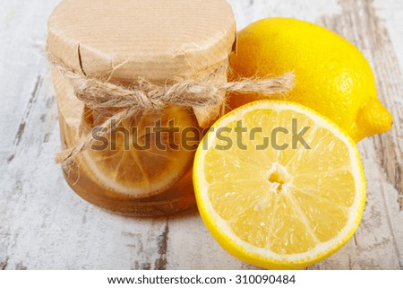 Lemon with honey in glass jar and fresh lemon on old wooden white table, concept of healthy food, nutrition and strengthening immunity